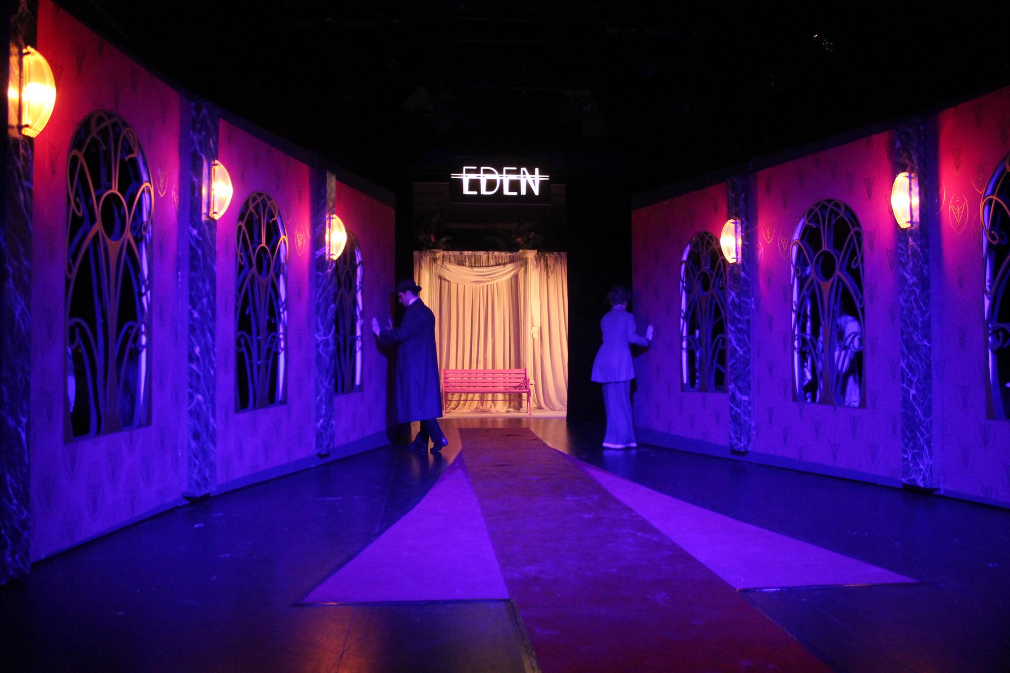 Rosa und Karl
        am Theater Osnabrück 2019 in Regie von Sophia Barthelmes. Zwei
        düstre Hotelwände mit Fenstern und Wandleuchten öffnen sich
        trichterförmig zu einer kitschigen Kulisse mit rosa Bank,
        darüber leuchtet der Schriftzug "Eden".